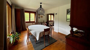 A dining area with a table, chairs, a hanging light fixture, and a potted plant.