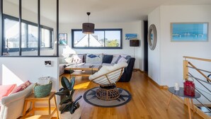 Una sala de estar moderna con un sofá, una mesa de centro, un sillón colgante y un amplio ventanal.