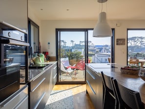 A modern kitchen with a large window, a dining area with a table and chairs, and a view of the outside.