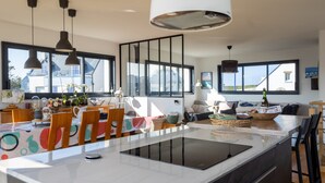 Una cocina moderna con una isla central, iluminación colgante y ventanas amplias.