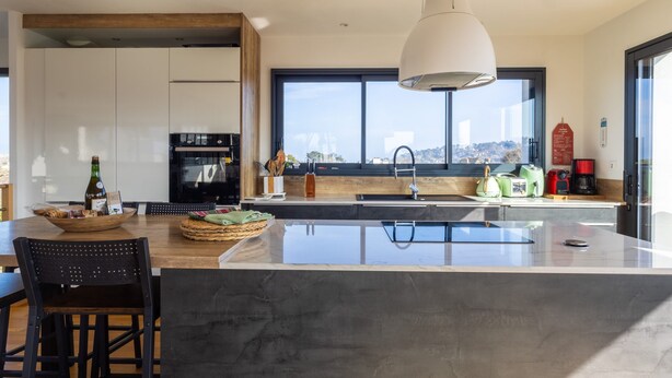 Una cocina moderna con una isla grande, horno empotrado y vistas a la ciudad.