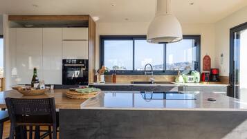 A modern kitchen with a large island, a built-in oven, and a view of the city.