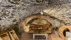 A stone-walled room with a leather sofa, a wooden coffee table, and a wooden barrel. - Country House 'Matalí' with Private Terrace, Wi-Fi and Air Conditioning (Espolla)