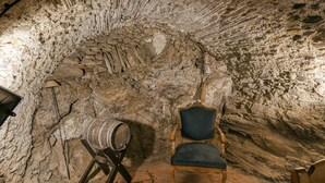 A stone-walled room with a wooden chair and a barrel. - Country House 'Matalí' with Private Terrace, Wi-Fi and Air Conditioning (Espolla)