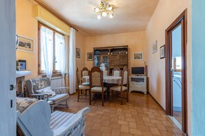 Un comedor con mesa, sillas, un televisor y un mueble con puertas de vidrio.