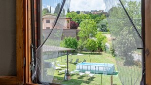 A view through a window with a view of a backyard, including a swimming pool and outdoor furniture.