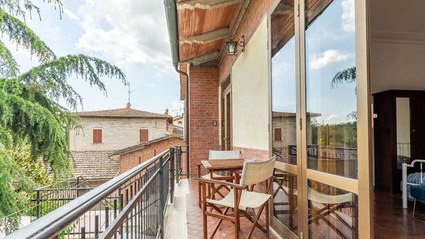 A balcony with a table and chairs, a view of neighboring buildings, and a railing.