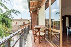Un balcón con mesa y sillas, vistas a edificios vecinos y una barandilla.