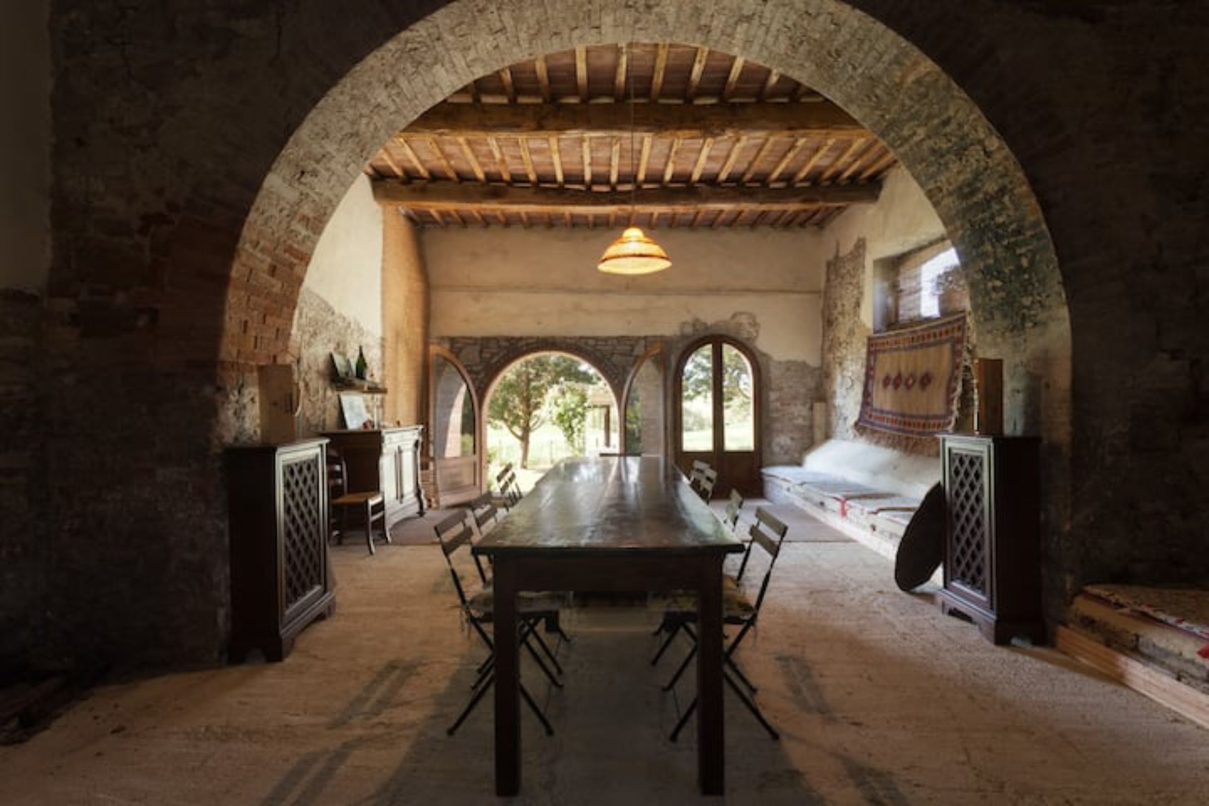 Un espace repas avec une longue table, des chaises et un plafond en arc de cercle.