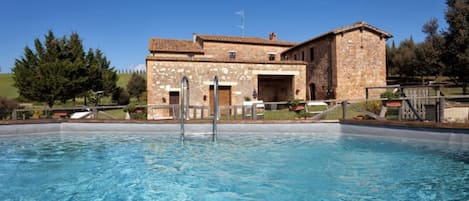 A stone building with a swimming pool in front.