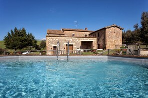 A stone building with a swimming pool in front.