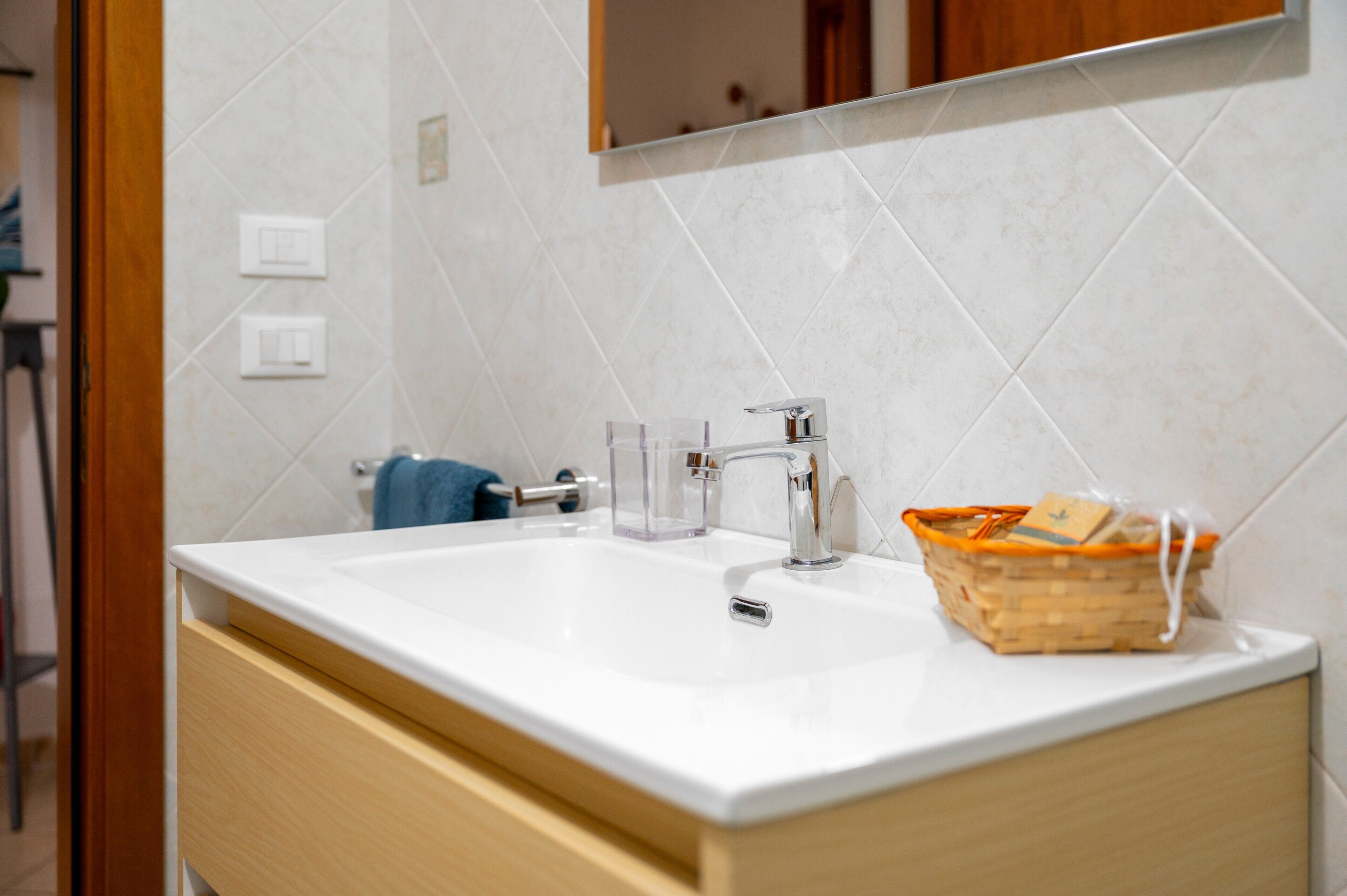 Un baño con un lavamanos blanco, un espejo encima y un armario de madera debajo.