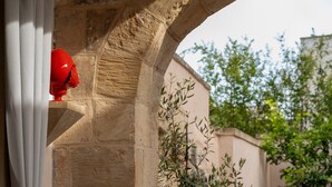 Un arco de piedra, un objeto rojo sobre una repisa y una pared con vegetación.