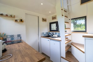 A compact kitchen with a sink, wooden cabinets, and a window with a view of greenery.