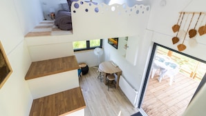 A multi-level interior with a staircase, a dining area, and a view to an outdoor deck. - Tiny House in Saint-Cernin-de-l'Herm – Shared Pool & Relaxing Stay for 4 Guests (SAINT-CERNIN-DE-L'HERM)