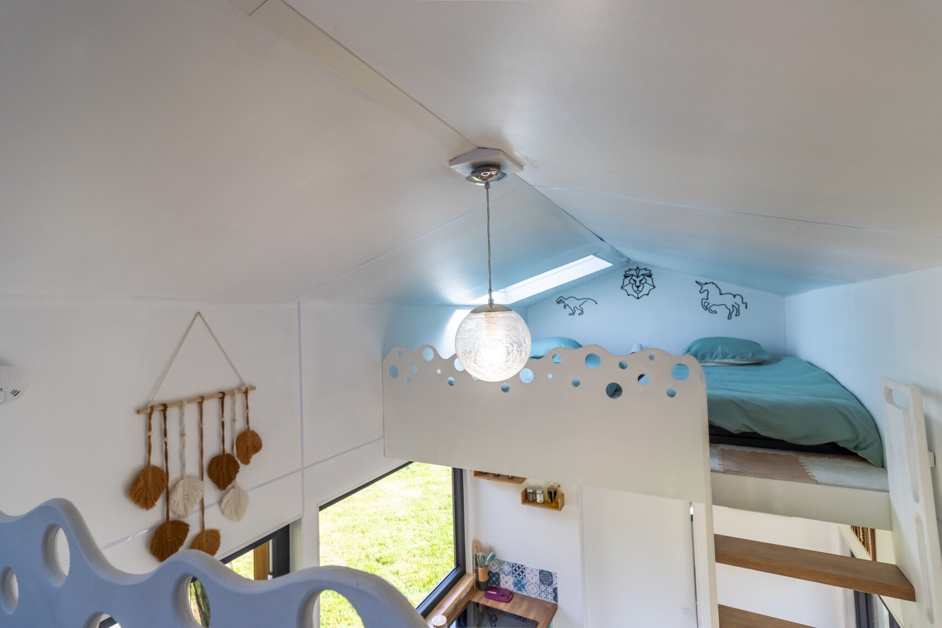 Een slaapkamer met stapelbed, dakraam, decoratie en uitzicht op de natuur.