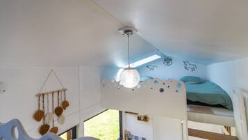Een slaapkamer met stapelbed, dakraam, decoratie en uitzicht op de natuur.