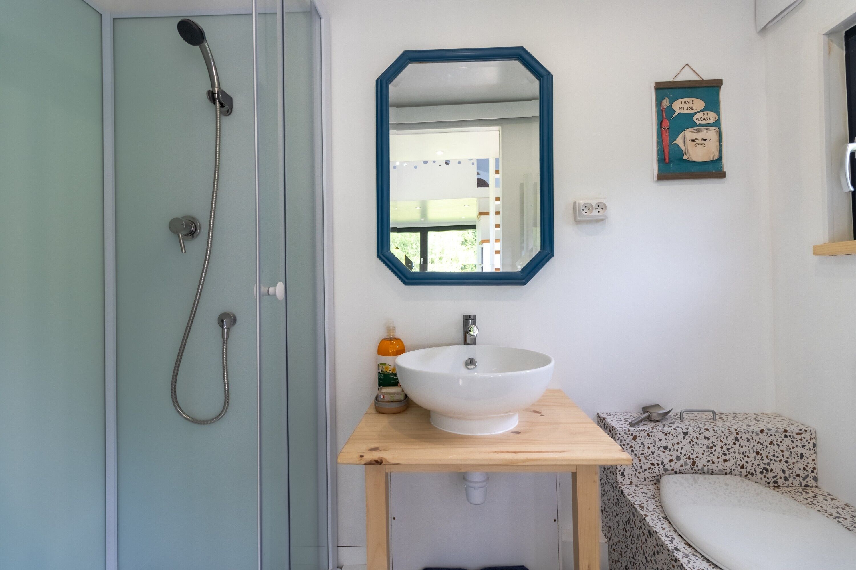 Een badkamer met een douche, wastafel, spiegel en toilet.