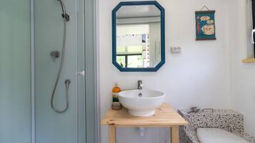Een badkamer met een douche, wastafel, spiegel en toilet.
