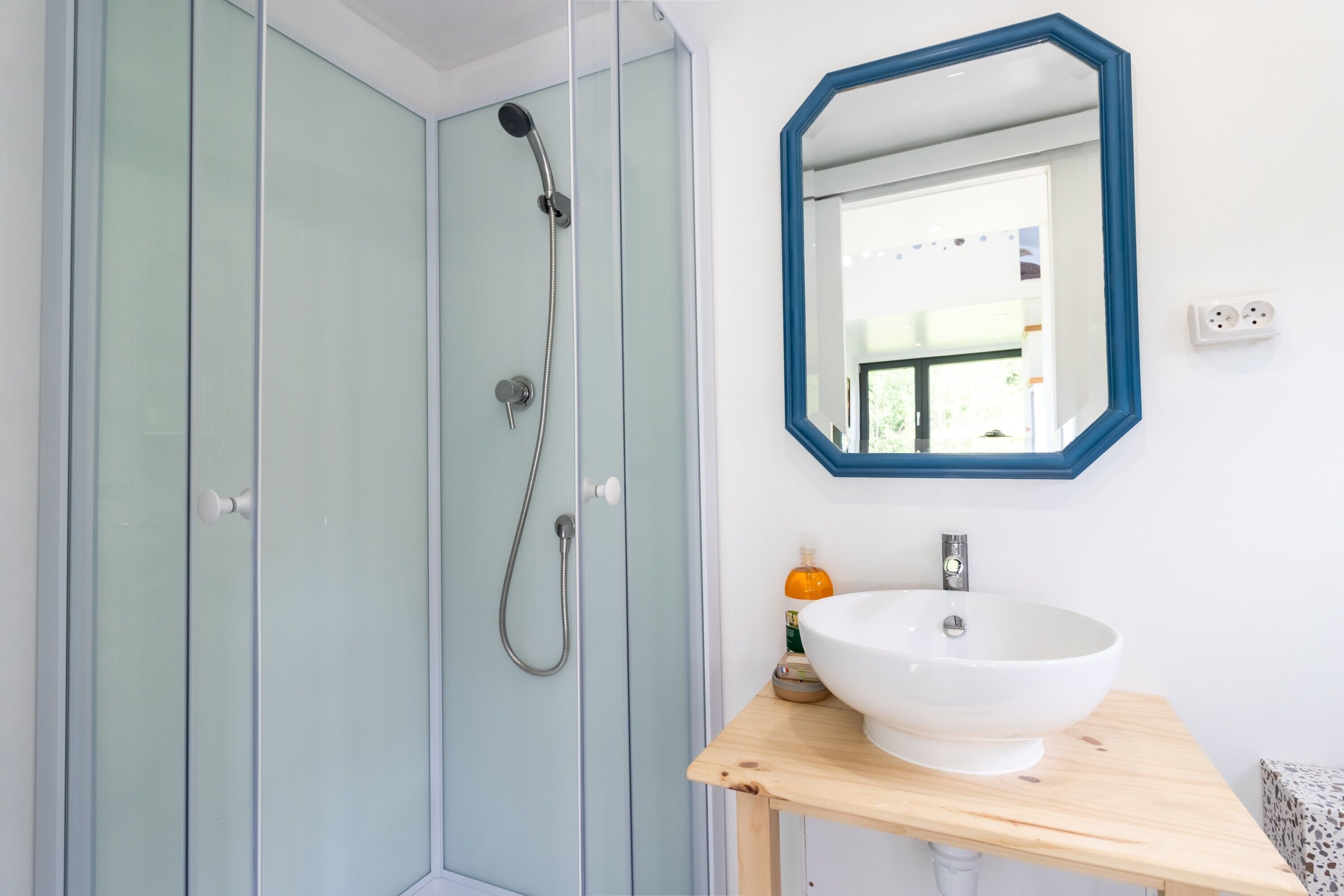 Ein Badezimmer mit Dusche, Waschbecken und Spiegel.
