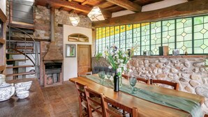 Un comedor rústico con pared de piedra, techo de madera y chimenea.
