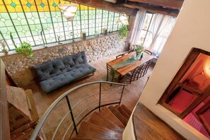 A staircase leading to a dining area with a stone wall, a sofa, and a fireplace.