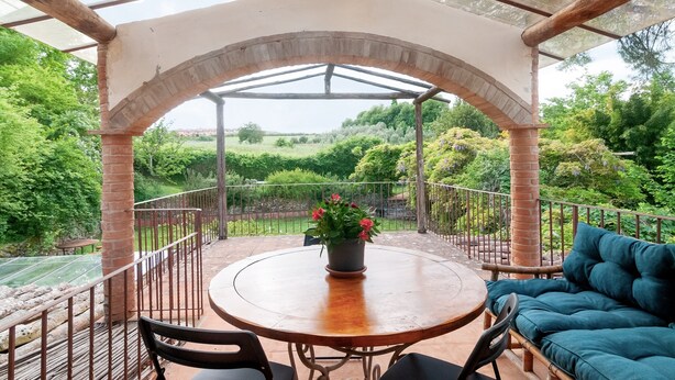 Un patio exterior con una mesa redonda, sillas, un sofá y una planta en maceta.