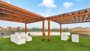 A covered outdoor seating area with white benches and a wooden pergola. - Vacation 'Punta Calma' with Sea View, Shared Pool and Wi-Fi (Majanicho)