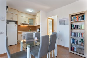 Una cocina moderna con comedor, una estantería y una pequeña mesa con sillas.