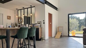 A modern kitchen with a bar area, a large mirror, and a sliding door leading to a garden. - Cozy home in Valaurie (Valaurie)