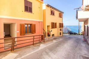 Un vicolo stretto con edifici, una ringhiera metallica e vista sul mare.