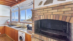 Una cucina con forno a mattoni, mobili in legno, una lavatrice e vista dalla finestra.