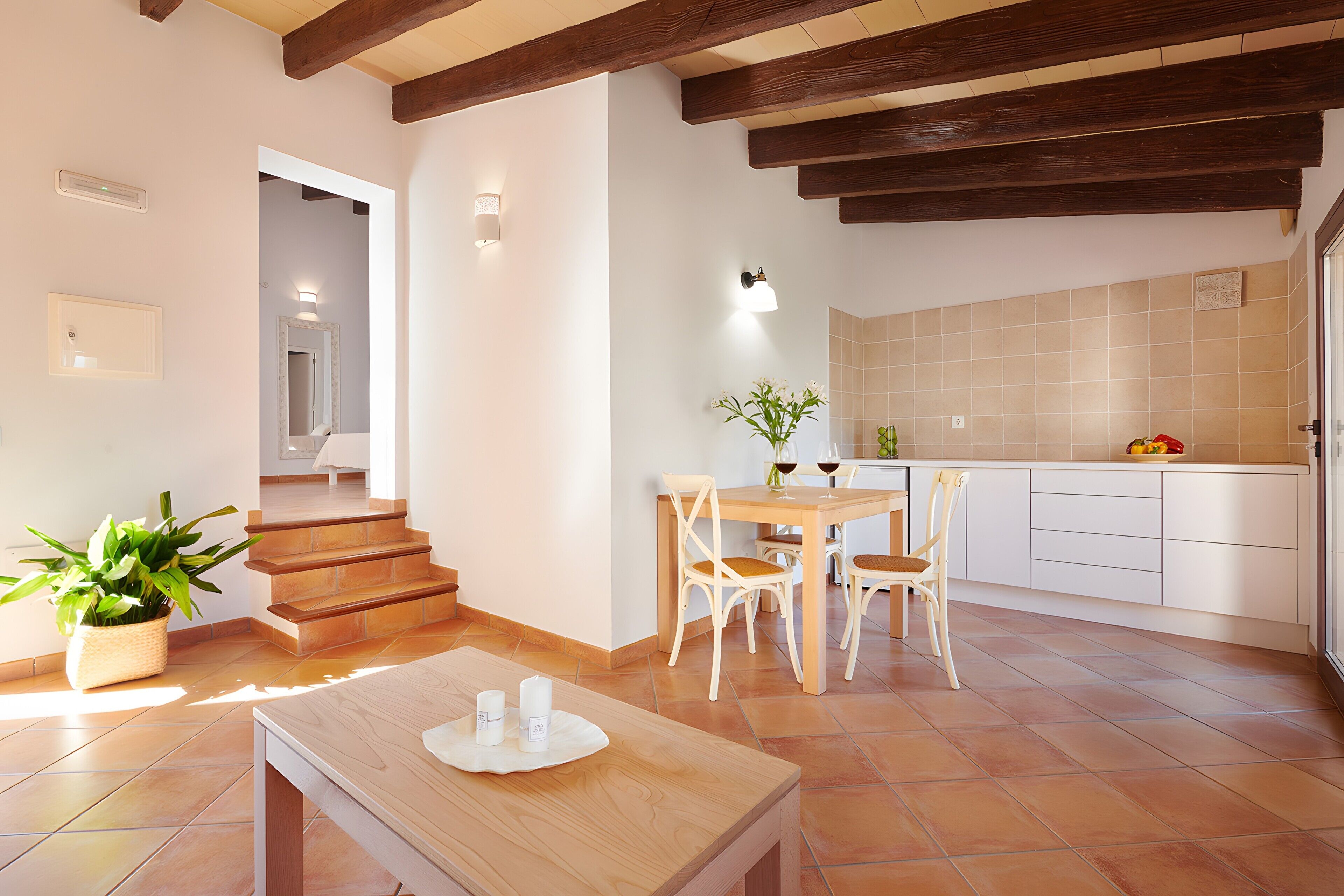 Una cocina moderna con zona de comedor, escalera de madera y una planta en maceta.