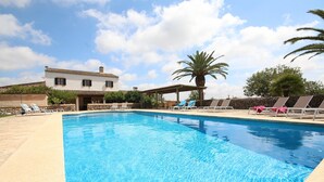 Una piscina con sillas de descanso, una palmera y un edificio al fondo.