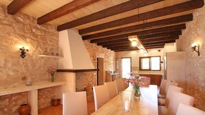 Un comedor con mesa de madera, sillas, paredes de piedra y vigas de madera a la vista.