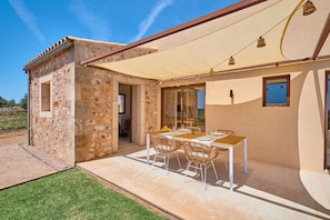 A stone building with a patio, outdoor table, and chairs.