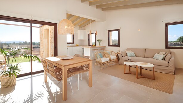 A spacious living area with a dining table, sofa, and chairs, large windows, and a view of the outdoors. - Rural House 'Son Rossinyol Nou - Ses Figueretes' with Mountain Views, Private Pool and Wi-Fi (Illes Balears)