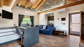 A modern kitchen with a bar area, a seating area with a sofa, and a view of the outdoors. - Holiday Home 'Alpine A&S' with Mountain View, Wi-Fi and Air Conditioning (Aymavilles)