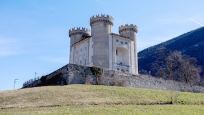 A castle with two prominent towers, a stone wall, and a hilly backdrop. - Holiday Home 'Alpine A&S' with Mountain View, Wi-Fi and Air Conditioning (Aymavilles)