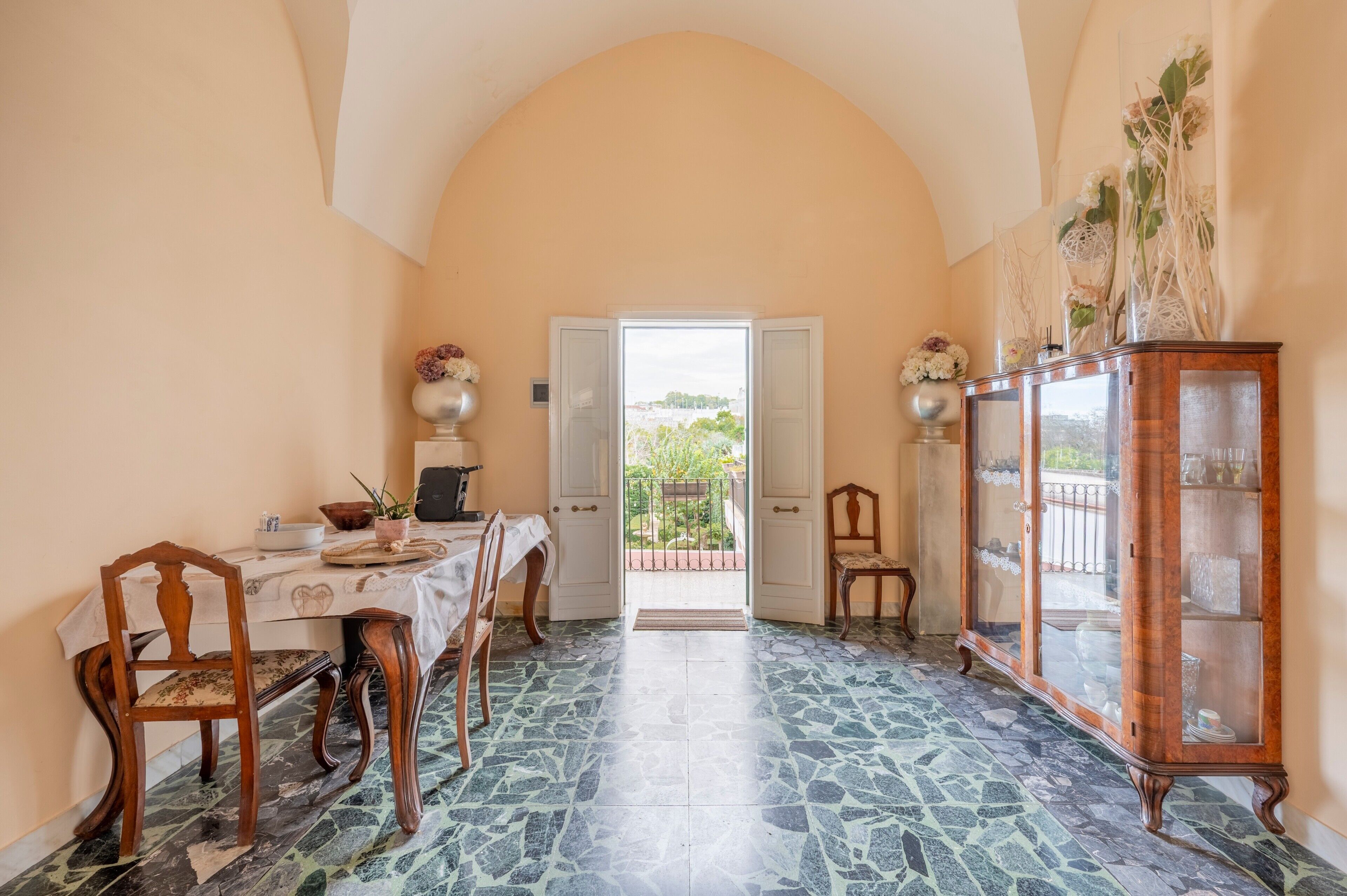 A dining area with a table and chairs, a cabinet, and a view through an open door.