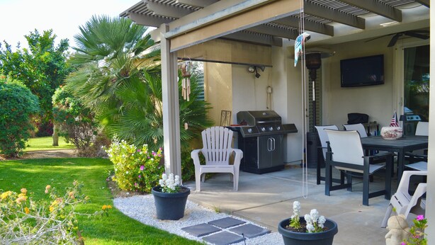 An outdoor patio with a grill, seating, and a TV. - Resort Style Home- Pool Table- Walking Distance to Coachella Fest & Stagecoach (Indio)
