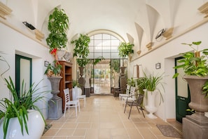Un couloir intérieur doté de plafonds en forme d’arc, de plantes en pot et d’espaces aménagés pour s’asseoir.
