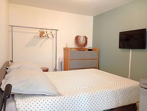 Ein Schlafzimmer mit einem Bett, einem Kleiderschrank, einem Fernseher und einem Wandheizkörper.