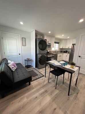 Un espacio habitable pequeño con sofá, mesa de comedor y kitchenette.