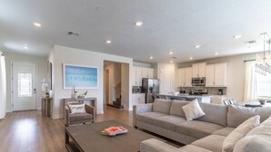 A spacious living room with a sofa, coffee table, and a view of the kitchen. - 284 Encore at Reunion (Kissimmee)