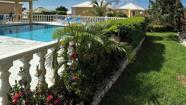 A pool area with a white fence, palm trees, and a clear sky. -  Pelican Key Studio-pool, near the beach. The best area on Dutch side! (Pelican Key)