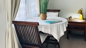 A room with a round table, a wooden chair, a small potted plant, a lamp, and a window with curtains. -  Pelican Key Studio-pool, near the beach. The best area on Dutch side! (Pelican Key)