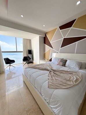 A modern bedroom with a large bed, a view of the ocean, and a geometric wall design. - Departamento de lujo Yoo-Panamá 34B  (Panama City)