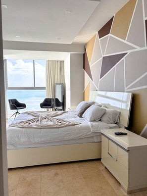 A modern hotel room with a large bed, a bedside table, a TV, and a view of the sea. - Departamento de lujo Yoo-Panamá 34B  (Panama City)
