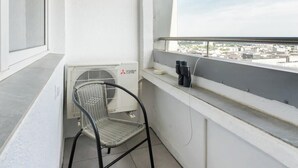A balcony with a metal chair, a radiator, and a window overlooking a cityscape. - Central Panorama Apartment | Chmielna 35 (Warszawa)